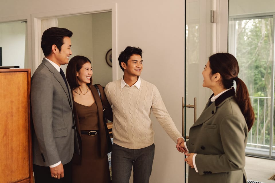 A couple being welcomed into a bright modern apartment by a friendly agent